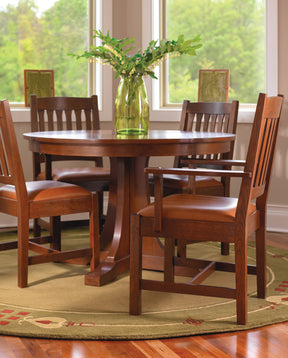A Round Pedestal Dining Table surrounded by Cottage Side and Arm Chairs with orange leather seats