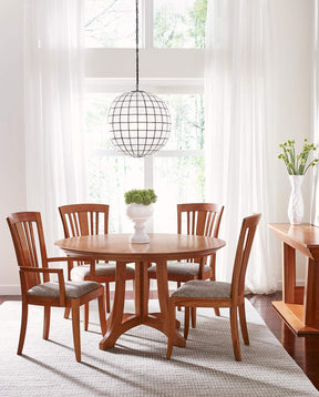 Lifestyle of a Highlands Round Dining Table surrounded by four Highlands Bayonne Side and Arm Chairs in front of a large floor to ceiling window