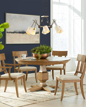 Lifestyle of a St. Lawrence Round Dining Table surrounded by four Curved Arm and Side Chairs in front of a dark blue wall