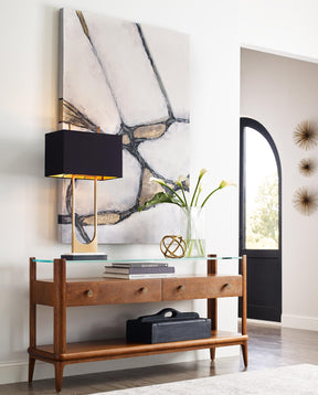 A large white, black, and gold painting is mounted on a white wall with a Martine Glass-Top Console Table underneath it