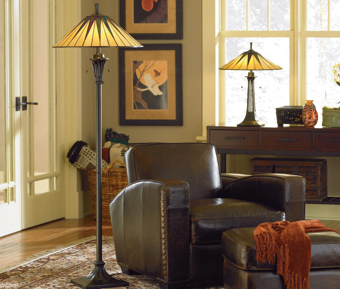 A tall floor lamp sits next to a dark brown leather chair and ottoman