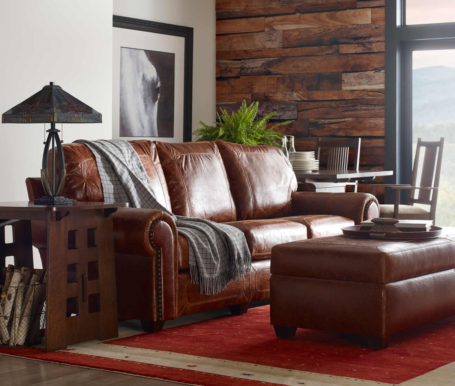 Lifestyle of a Santa Fe Sofa with a matching Santa Fe Ottoman in front of it, there is an end table to the side of the sofa with an iron lamp on top of it