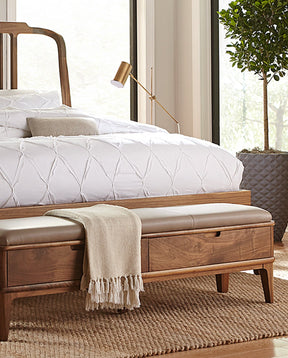 Walnut Grove bench against a Walnut Grove bed with a light brown leather on top and cream colored blanket draping over it