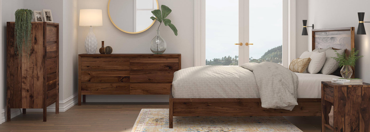 Fulton Lane Beckett bedroom set displaying a tall chest, dresser, side view of the bed, and nightstand in front of two glass doors.