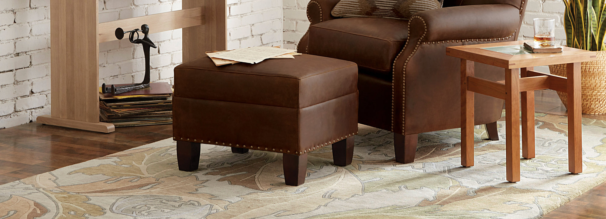 Close up of a dark brown leather chair and ottoman on top of a Curling Vine Rug