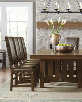 Mission dining room table lined with four leather Mission dining chairs with a stone wall behind it