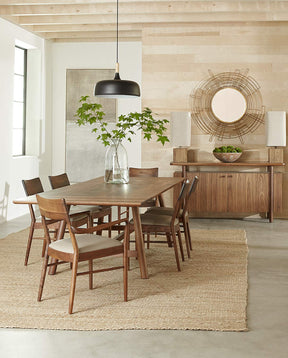 Walnut Grove dining table and sideboard decorated with glass vases and greenery. The table sits on top of a tan rug.