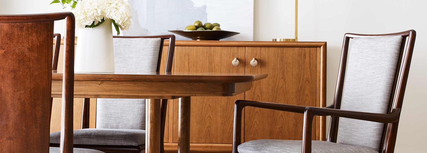 Close up of a Martine dining table and upholstered chairs, with a matching sideboard behind the table