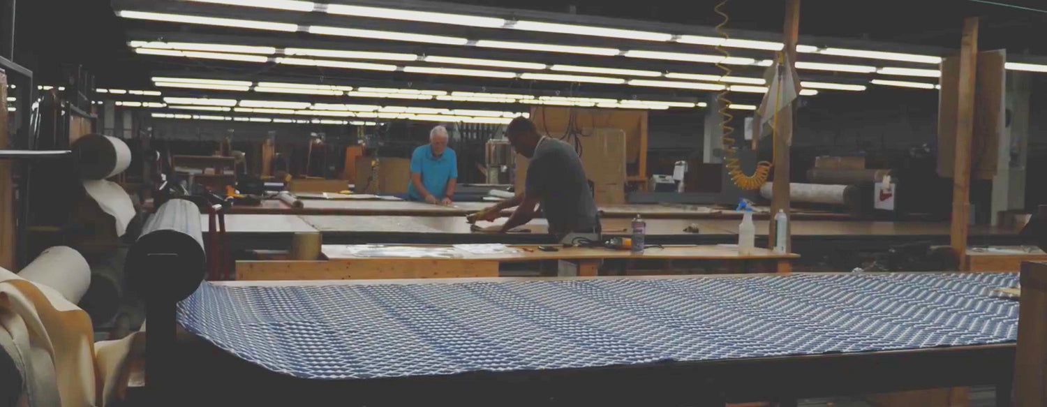 Factory workers work with spools of fabric