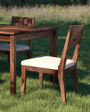 A Beckett Dining Table and Chairs sit outside on lush green grass, a field is blurred out in the background