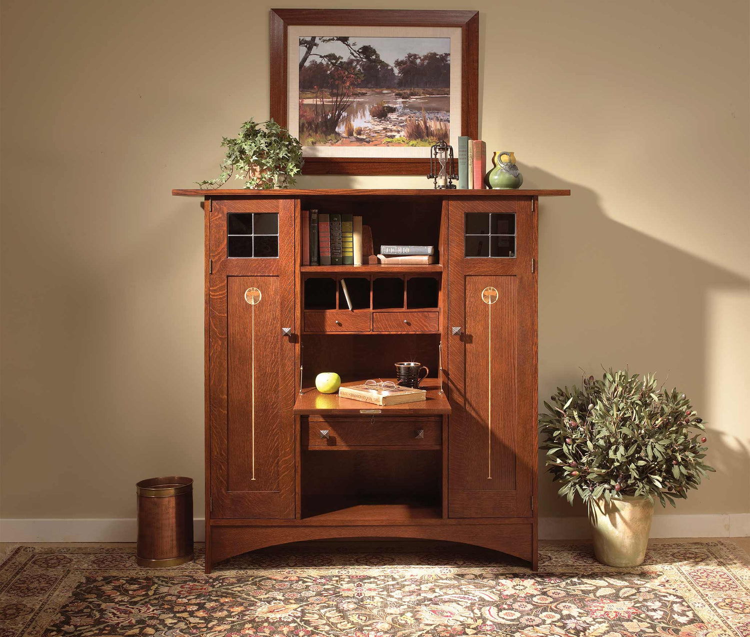 Lifestyle of an Ellis Fall-Front Bookcase with Wood Doors with a painting above it, plants and books on top, and books inside of it.