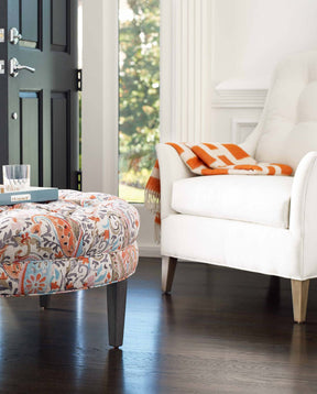 Floral print Stickley Ottoman in front of a white upholstered accent chair.