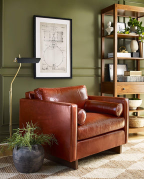 Lifestyle of a dark brown leather Walnut Grove Paxton Chair against a dark green wall