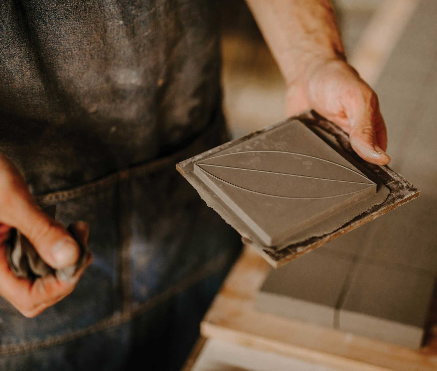 A Factory worker holds an unfinished tile in their hand