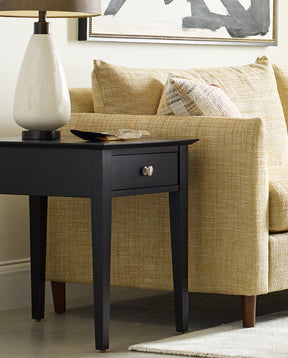 Lifestyle of a Gable Road One-Drawer End Table in the color 809-EBONY with a white lamp on top of it, it is next to a light green upholstered sofa