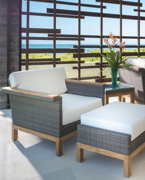 Stickley Outdoor Accent Chair and matching ottoman sitting in an outside patio, the sky in the background is light blue and there is an ocean below it