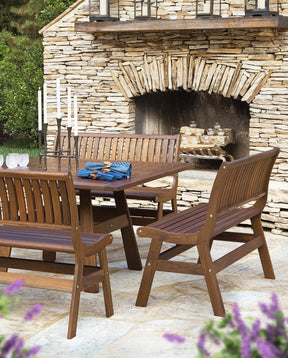 Outdoor Beechworth Square Dining Table with matching chairs are sitting in front of a large stone outdoor fireplace