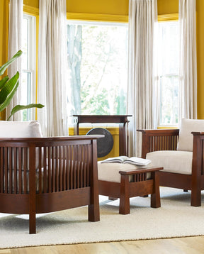 Lifestyle with two Park Slope Chairs and a Park Slope Ottoman between them. They are sitting in a bright yellow room with a large window.