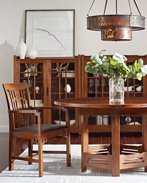 Lifestyle of the Thorsen Round Dining Table, with a Blacker House Arm Chair and two Gamble House Bookcases side by side behind them