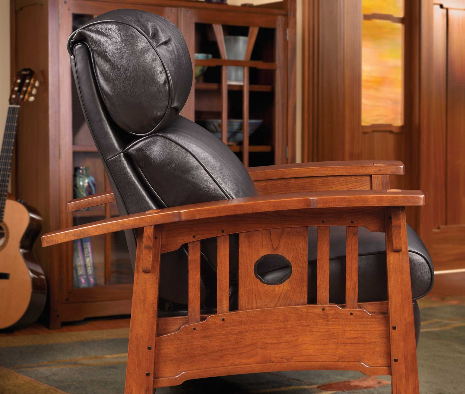 Lifestyle of a Tsuba Bustle-Back Recliner in front of a slightly out of focus Gamble House Bookcase