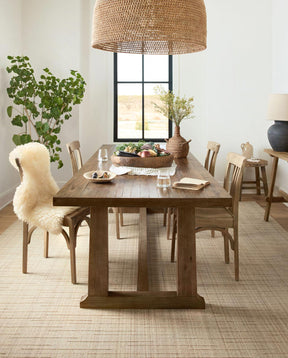 A wooden dining room set sits on top of a Loloi Brooks Oatmeal Rug