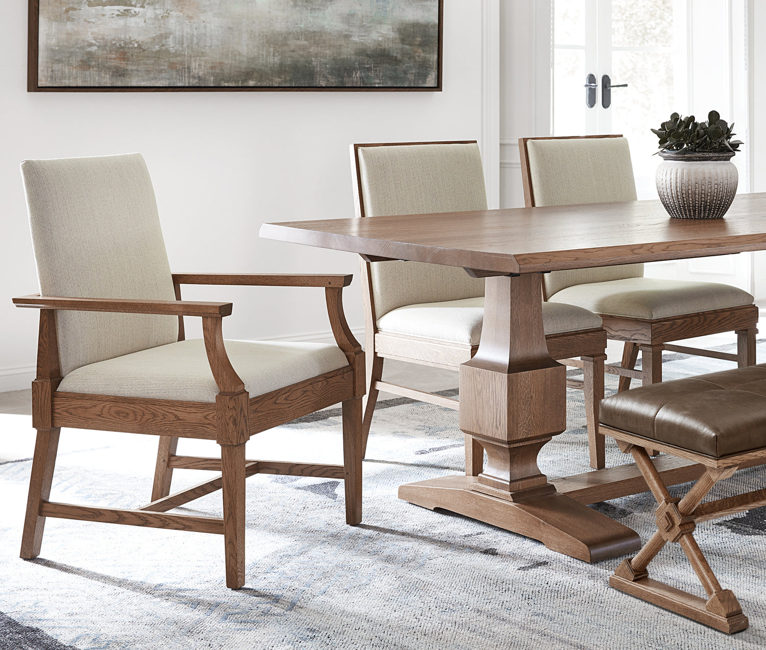 Lifestyle of a St. Lawrence Trestle Table with St. Lawrence Hostess Chair, two Arm Chairs, and a St. Lawrence bench surrounding the table.