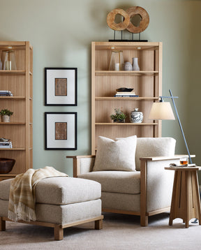 Lifestyle of Surrey Hills Wood-Frame Lounge Chair with an ottoman in front of it, behind the chair are two Surrey Hills Bookcases against a light green wall.