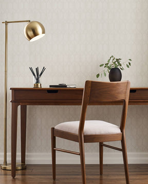Lifestyle of a Walnut Grove Desk with a Walnut Grove Side Chair slightly pulled out from it. There is a pen holder and small black potted vase on top of it and a gold floor lamp beside it.